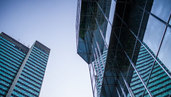 A dramatic view of tall skyscrapers with reflective glass surfaces under a clear sky.