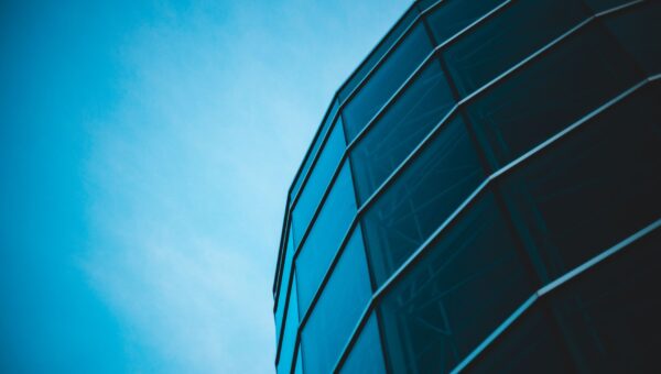 Low-angle view of modern glass architecture set against a bright blue sky, offering a minimalist and sleek design perspective
