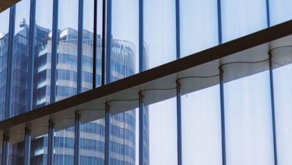Reflection of a modern office building captured through a glass window indoors.