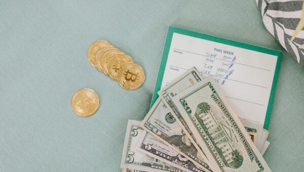 Close-up of U.S. dollars and Bitcoin coins placed on a weekly budget planner, symbolizing modern finance.
